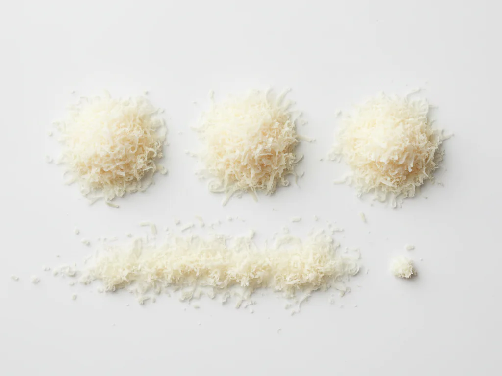 Rasp Parmezaanse kaas heel fijn met een microplane of fijne rasp. Meng een klein snufje door puree, geprakte groenten of havermout om smaak en voedingsstoffen toe te voegen. Zorg dat het volledig is opgenomen om klontjes te voorkomen.